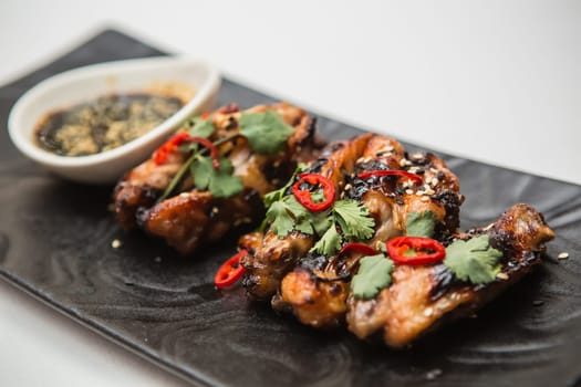 Hot organic chicken wings with red pepper on black dish