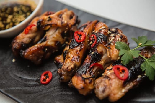 Hot organic chicken wings with red pepper on black dish