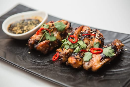 Hot organic chicken wings with red pepper on black dish