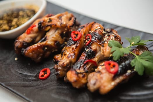 Hot organic chicken wings with red pepper on black dish