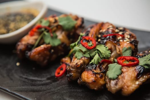 Hot organic chicken wings with red pepper on black dish