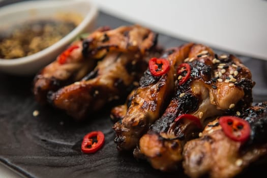 Hot organic chicken wings with red pepper on black dish