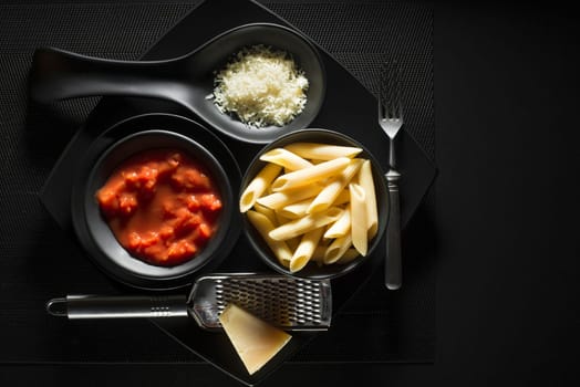 Penne pasta with tomatoes sauce and parmesan on black background