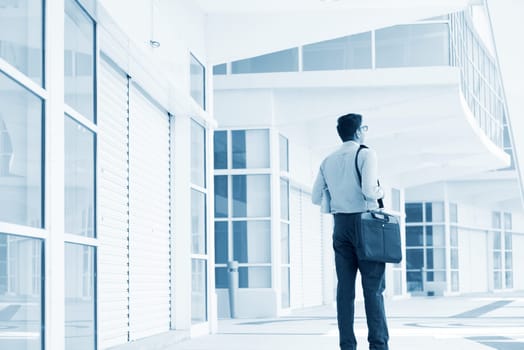 Young businessman walking through a modern office building.