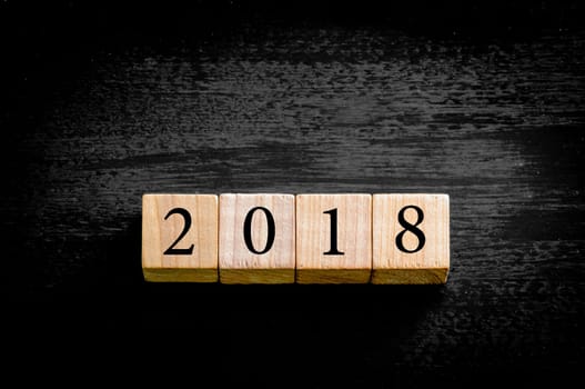Year 2018. Wooden small cubes with numbers isolated on black background with copy space available. New Year Concept image.