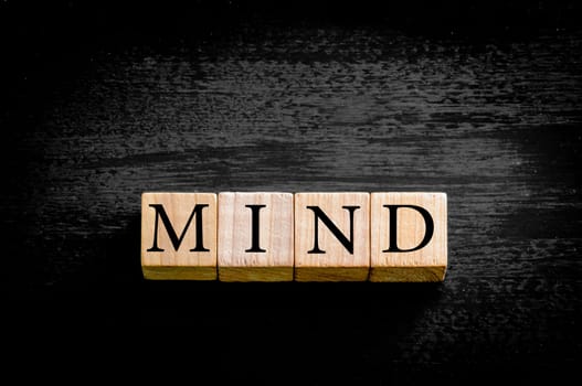 Word MIND. Wooden small cubes with letters isolated on black background with copy space available. Concept image.