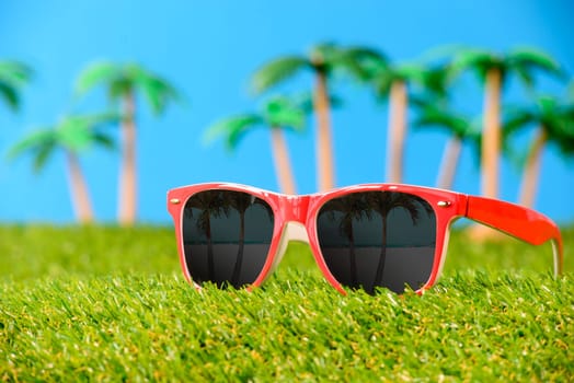 sunglasses on green grass with palm trees