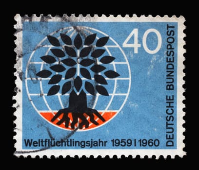 Stamp printed in Germany showing a stylized tree in a globe. World Refugee Year, circa 1960