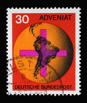 Stamp printed in Germany showing Cross in front of a globe with map of South America, “Adveniat,” aid movement of German Catholics for the Latin American church, circa 1967