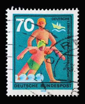 Stamp printed in Germany showing a rescuer pulls injuries out of the water, Voluntary help service lifesaving, circa 1970