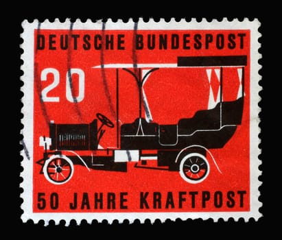 Stamp printed in Germany, shows a post bus from 1906 against a red background. The postage stamp was published on the occasion of 50 years of automobile post, circa 1955