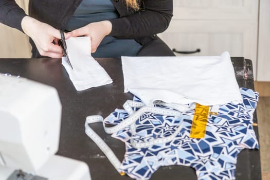 Top view of woman cutting with scissors fabric at home. Horizontally.