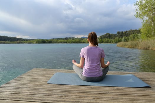 Back view of a woman doing yoga exercise in a lake