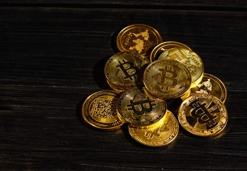 Leader in cryptocurrency bitcoin BTC on a top of coins against black wooden surface. Closeup golden coin with bitcoin logo. Stack of decentralized digital currency. Crypto payment. Electronic money