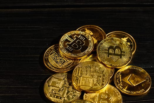 Leader in cryptocurrency bitcoin BTC on a top of coins against black wooden surface. Closeup golden coin with bitcoin logo. Stack of decentralized digital currency. Crypto payment. Electronic money