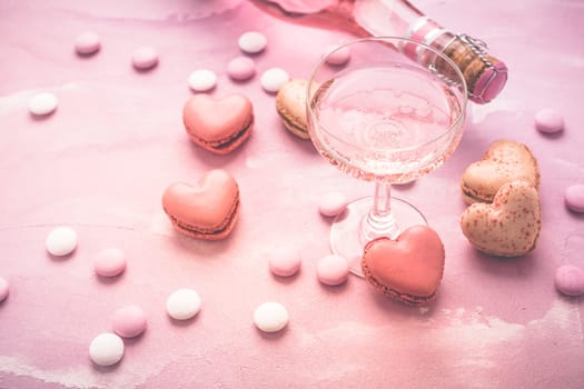 Happy Mothers Day - sweet macarons in heart shape and glass of rose sparkling wine with flowers in pink tone