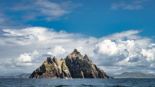 Cruise boat in front of Little Skellig island, habitat of Gannets, Morus Bassanus, with Irish coastline in the background, Ring of Kerry, Ireland