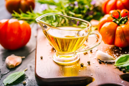 Italian cuisine - Olive oil, tomato and herbs on rustic cutting board