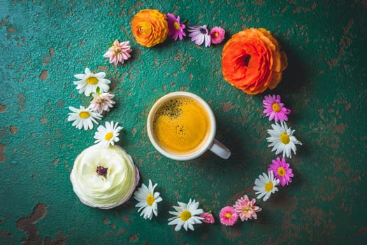Cup of coffee with variation of flowers on green background with copy space