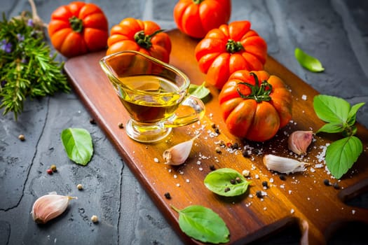 Italian cuisine - Olive oil, tomato and herbs on rustic cutting board