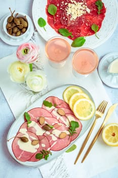 Appetizers - Vitello tonnato and beef Carpaccio with two glasses of rose wine.