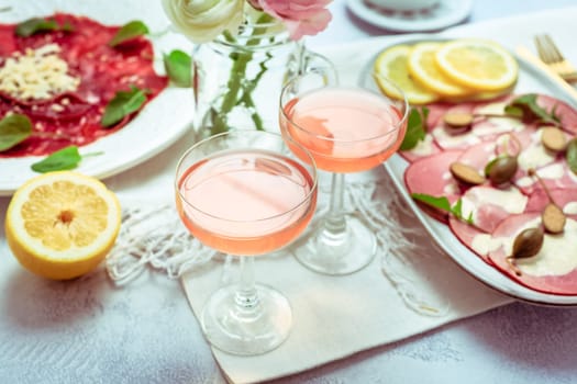 Appetizers - Vitello tonnato and beef Carpaccio with two glasses of rose wine.