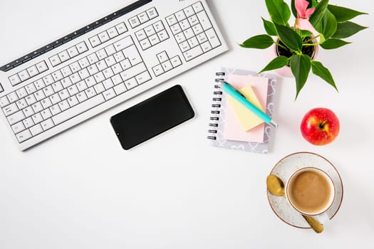 Workplace and office desk with coffee, apple, laptop, headset and smarthpone. Flatlay on white background.