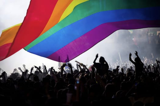 Pride community at a parade with hands raised and the LGBT flag - symbol of love and tolerance