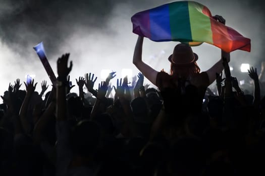 Pride community at a parade with hands raised and the LGBT flag - symbol of love and tolerance