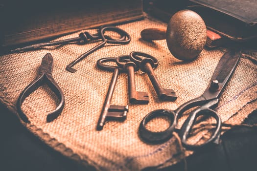 Old tools, books, keys and supplies on burlap in vintage style