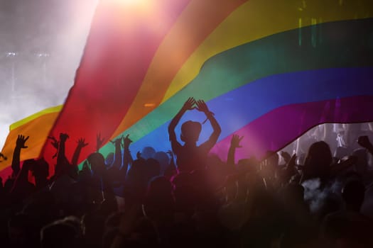 Pride community at a parade with hands raised and the LGBT flag - symbol of love and tolerance