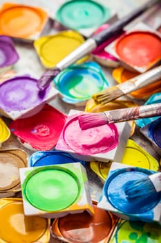 Set of colorful watercolor paints and paintbrushes for painting closeup. Selective focus.