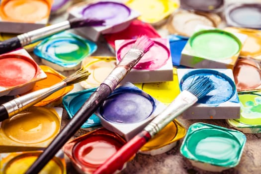 Set of colorful watercolor paints and paintbrushes for painting closeup. Selective focus.