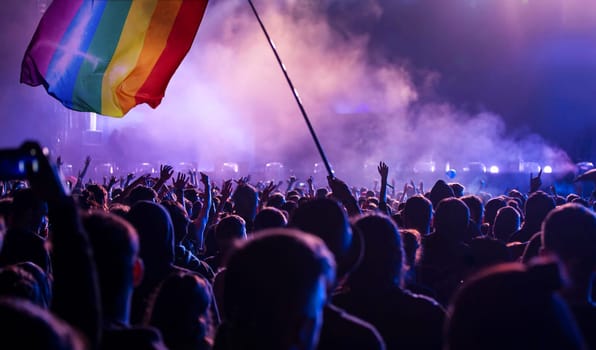 Pride community at a parade with hands raised and the LGBT flag - symbol of love and tolerance