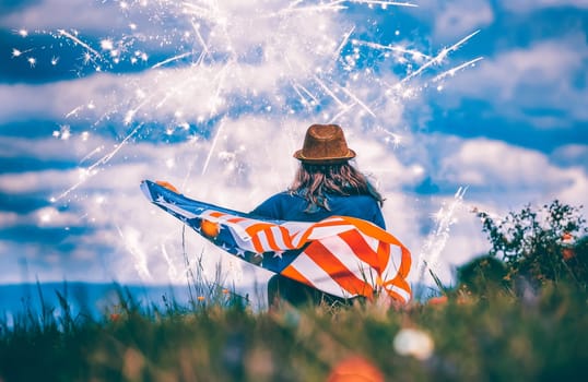 Young happy patriot girl holding the american flag under the 4th of July under fireworks.