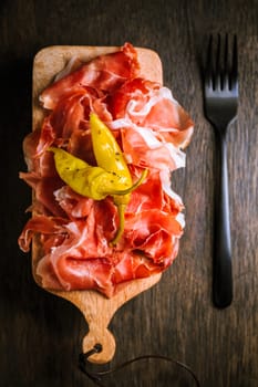 Prosciutto with grilled peppers - Italian dry ham with grilled green peppers on wooden table