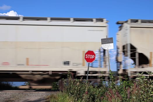 A train speeds past a stop sign at a crossing.