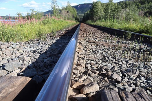 The shiny top view of a rail on a train track.