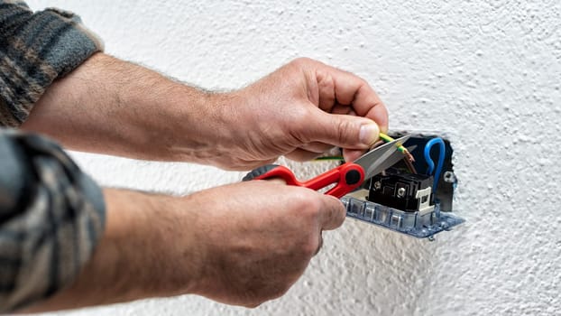 Electrician worker at work with scissors prepares the electrical cables of an electrical system. Construction industry.