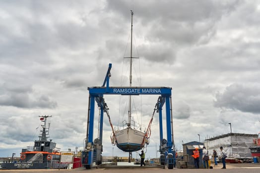 A lifting crane raises a yacht out of the water at Ramsgate Marina.
