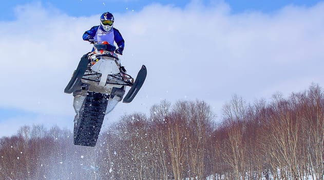 The Snowmobile in high jump above track. Selective focus