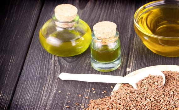 Sesame oil in glass and seeds on wooden background