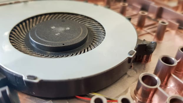 Closeup on a laptop cooler. Maintenance and prevention of the laptop cooling system. Electronic device repair concept. Dust and dirt on the computer fan. Disassembly of the computer