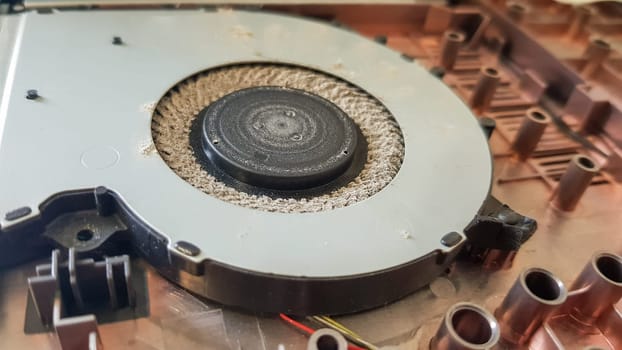 Closeup on a laptop cooler. Maintenance and prevention of the laptop cooling system. Electronic device repair concept. Dust and dirt on the computer fan. Disassembly of the computer