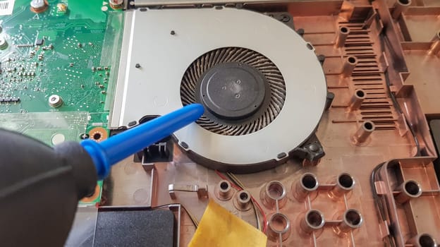 Closeup on a laptop cooler. Maintenance and prevention of the laptop cooling system. Electronic device repair concept. Dust and dirt on the computer fan. Disassembly of the computer