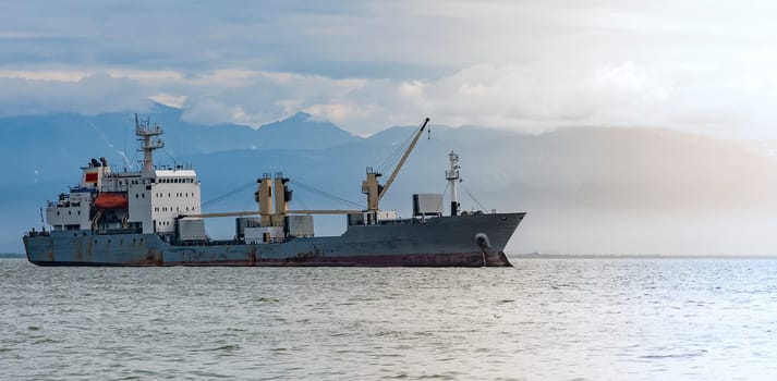 The Large cargo container ship sailing against the volcano