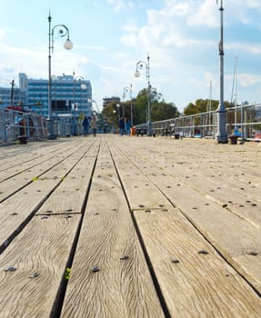 Wooden pier of marina with moored yachts and motorboats, hotels and apartments buildings in the background. Larnaca, Cyprus
