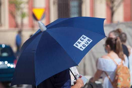 Male free tour guide with blue umbrella. Santa Cruz neighborhood, historic district of Seville, Spain