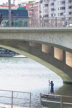 Paddle surfer under Triana Bridge of Seville, Spain. Guadalquivir River sports activities concept