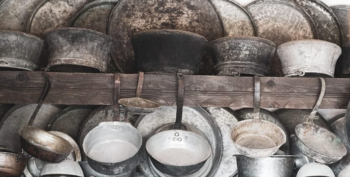 collection of old metal pan pot and kitchenware hanging on the wall in a traditional cooking kitchen